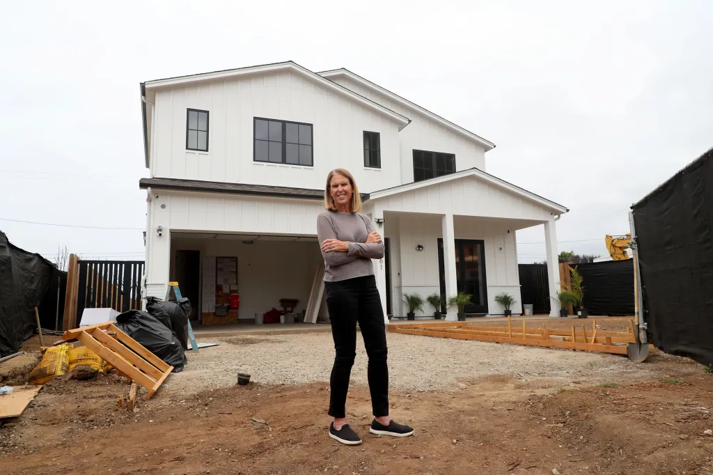 Sue Kohl stands proudly in front of her home in Pacific Palisades, which is being rebuilt after a devastating fire.