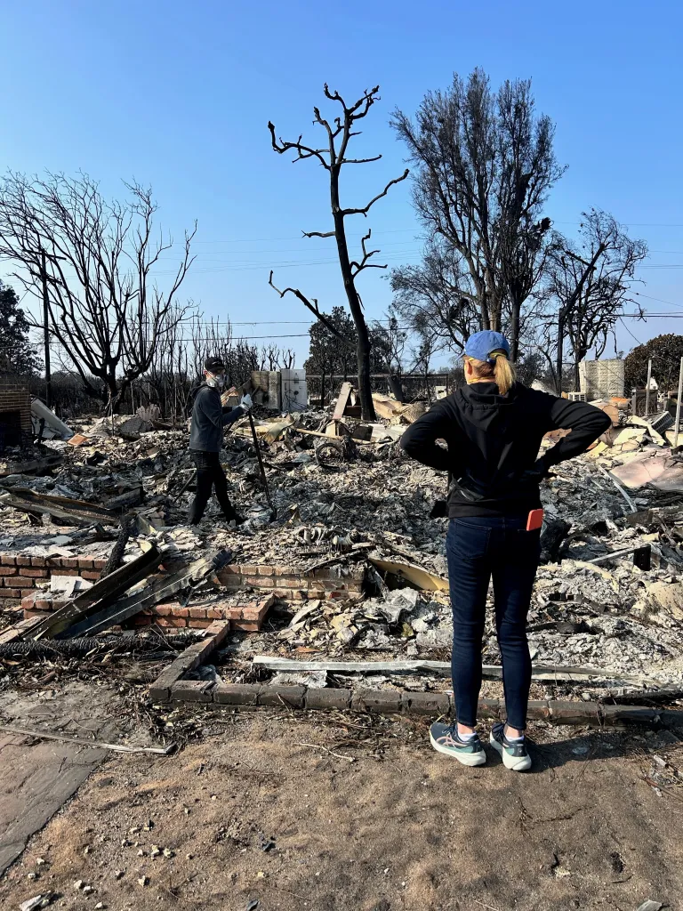 Sue Kohl standing outside her fire-damaged home in Pacific Palisades.