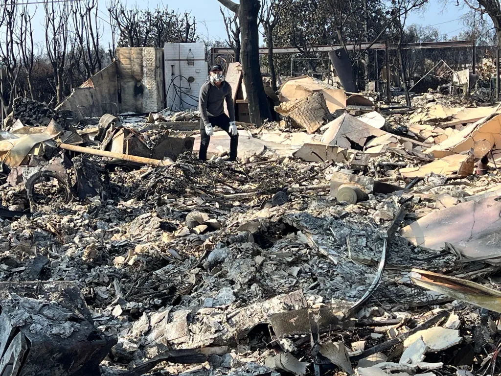 Sue Kohl standing in the rubble of her home after a fire.