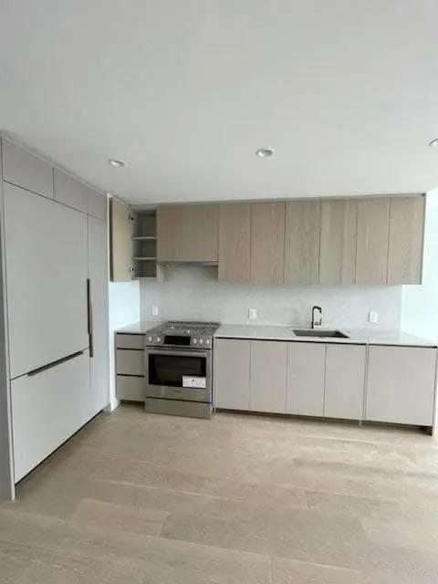 Kitchen interior with light-colored cabinets, a stainless steel stove, and a sink.