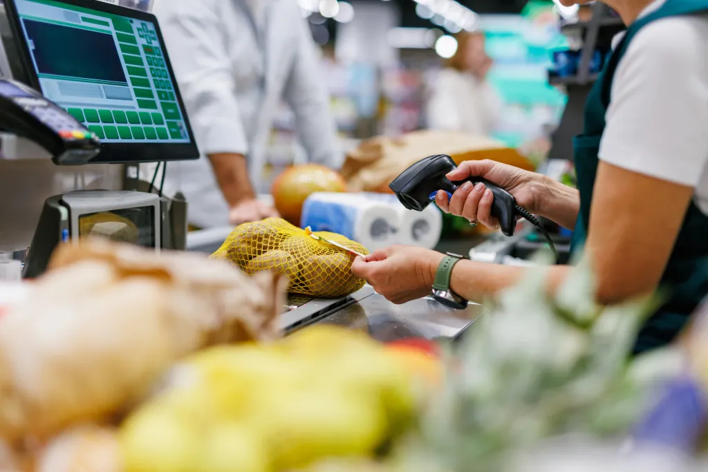 Cashier scanning potatoes at a supermarket checkout counter.
