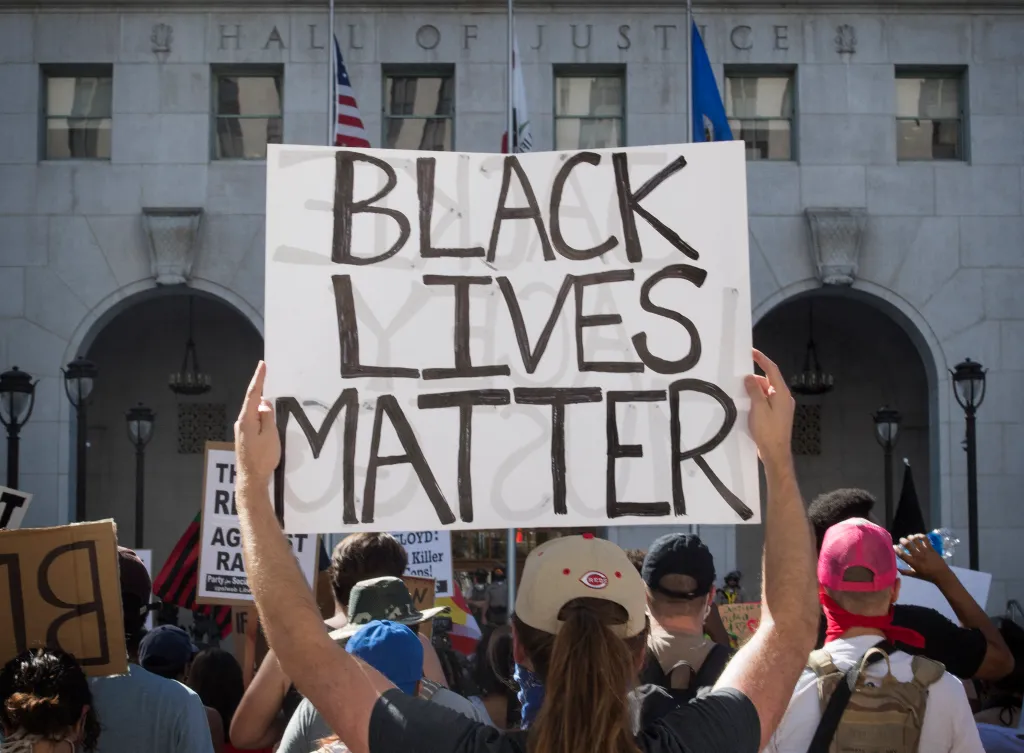 A person at a Black Lives Matter protest holds up a sign that reads 