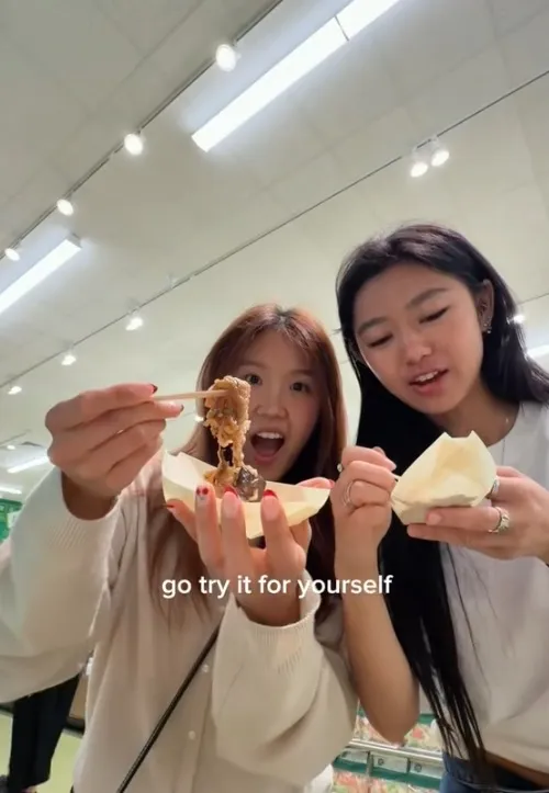 Two young women eating street food with 