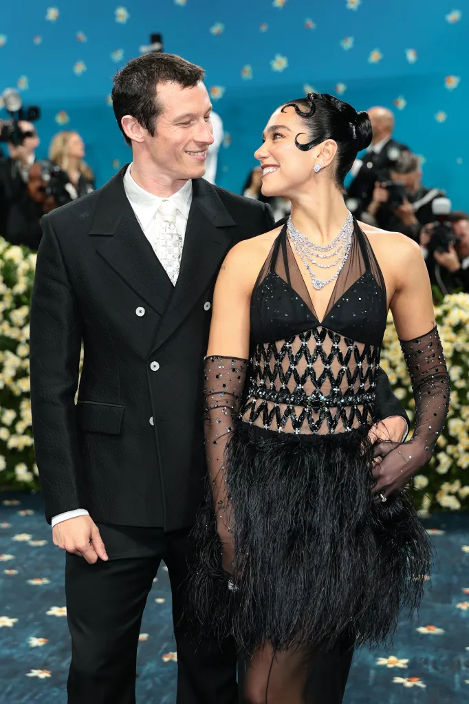 Callum Turner and Dua Lipa smiling at each other at the Met Gala.