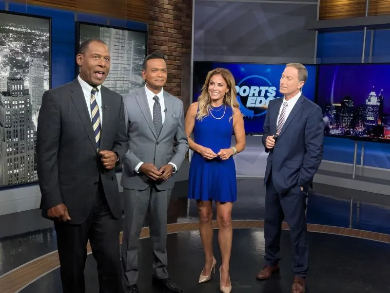 Taryn Asher with three male co-anchors in a TV studio.