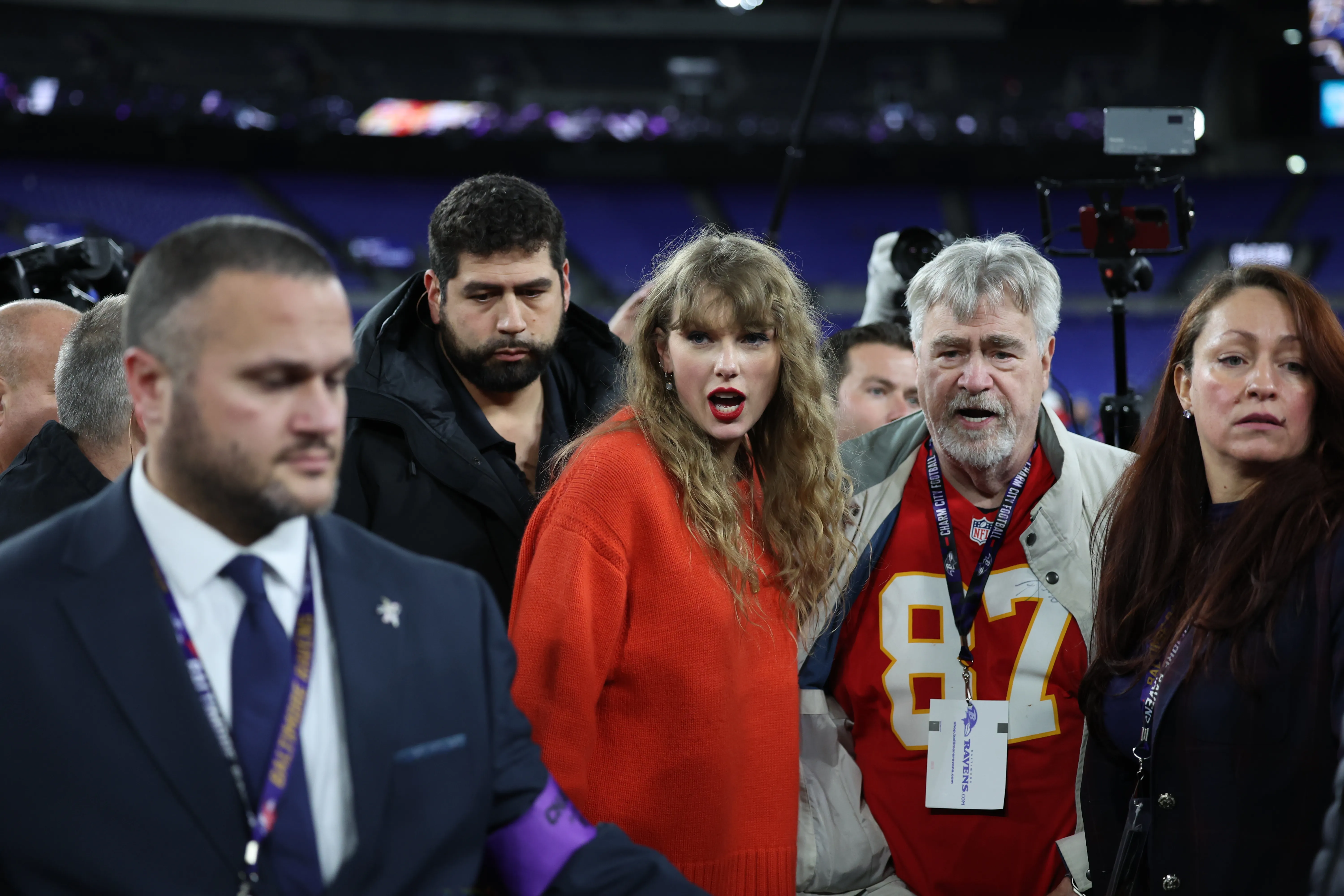 Taylor Swift and Ed Kelce walking off the field after a game.