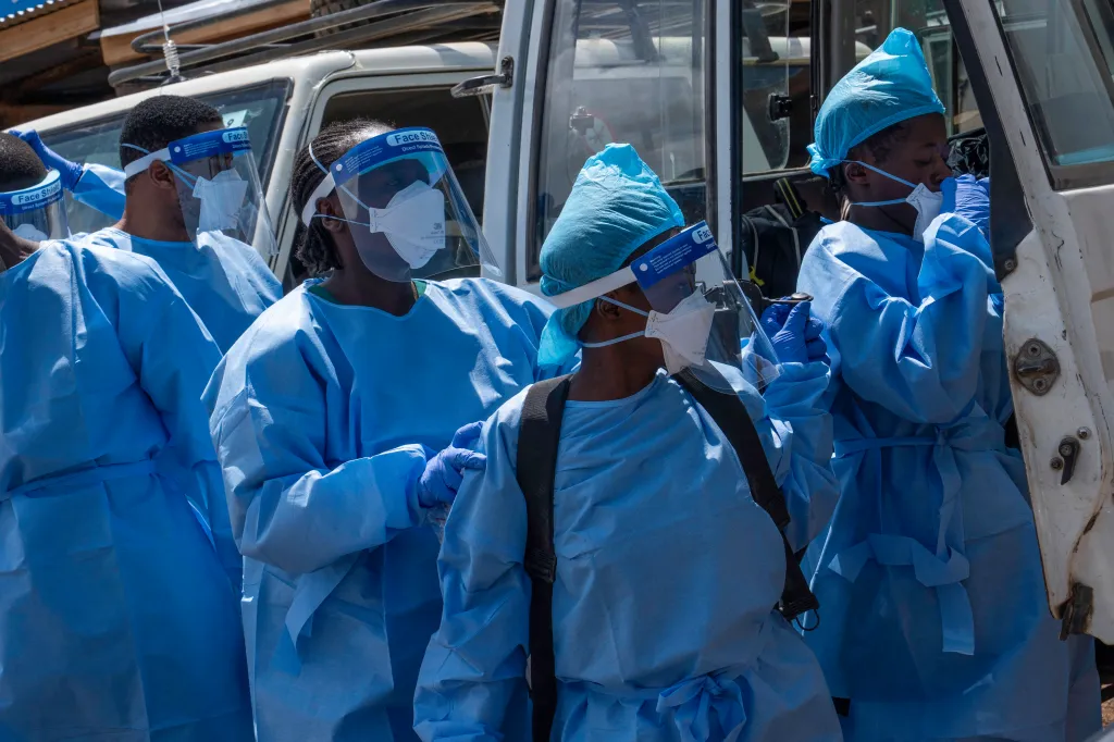 Ebola response team members in protective gear preparing to retrieve a body.