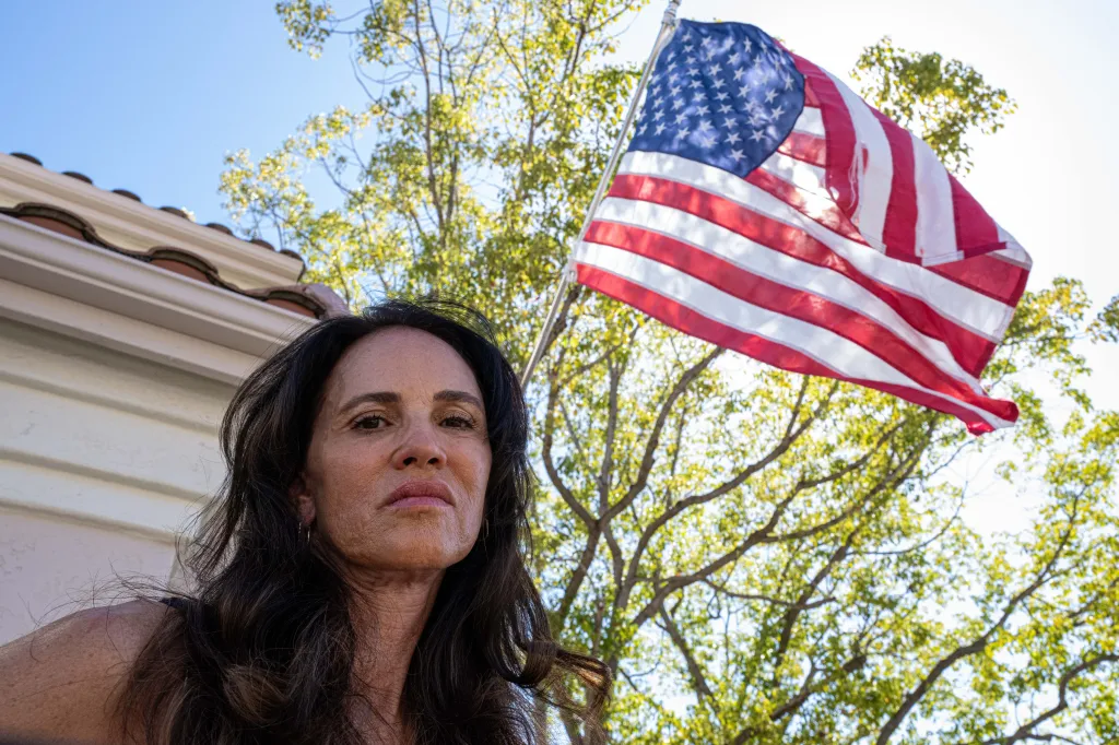 Terri Collins in front of her home with an American flag displayed.