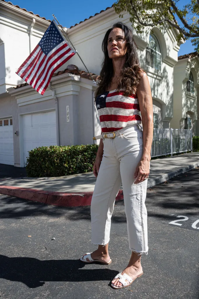 Terri Collins, wearing an American flag top, stands in front of her home with an American flag displayed.