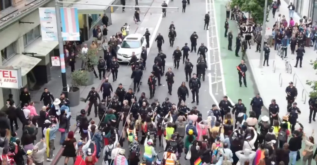 Overhead view of a street demonstration with a large crowd and numerous police officers.