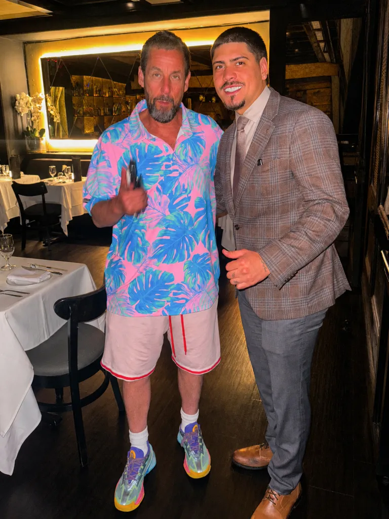 Adam Sandler and a fan posing for a photo in a restaurant.