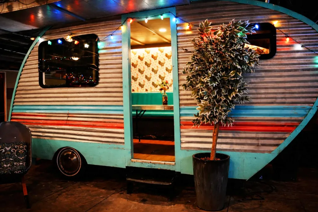 Trailer Park After Dark restaurant in San Diego, made from a retro trailer with a lit doorway and colorful string lights.
