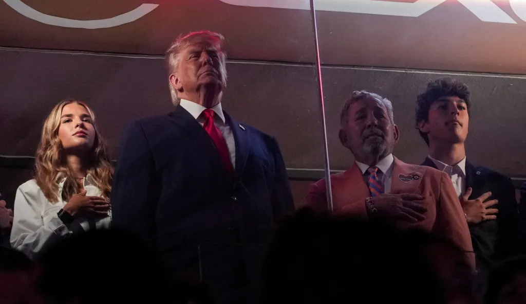 Donald Trump, his granddaughter, and James Dolan with hands over their hearts for the national anthem at the NBA Finals.