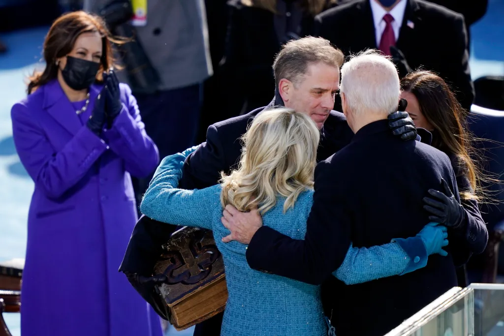 President Joe Biden embracing First Lady Dr. Jill Biden after his inauguration, with son Hunter Biden, daughter Ashley Biden, and Vice President Kamala Harris watching.