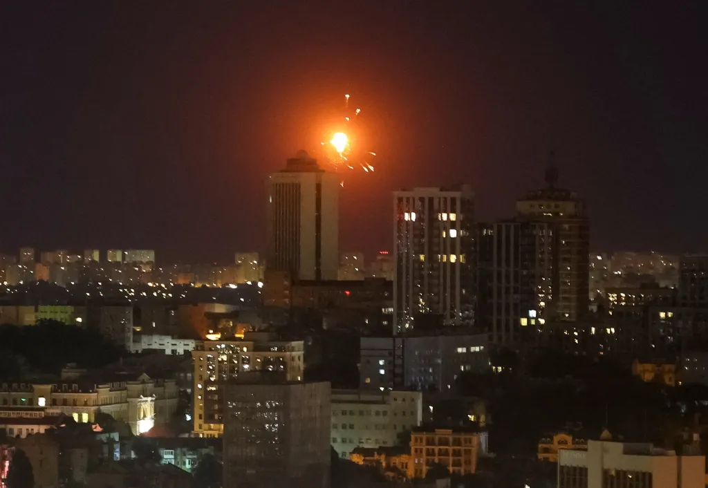 An explosion lights up the night sky above a cityscape during a Russian drone and missile strike in Kyiv.