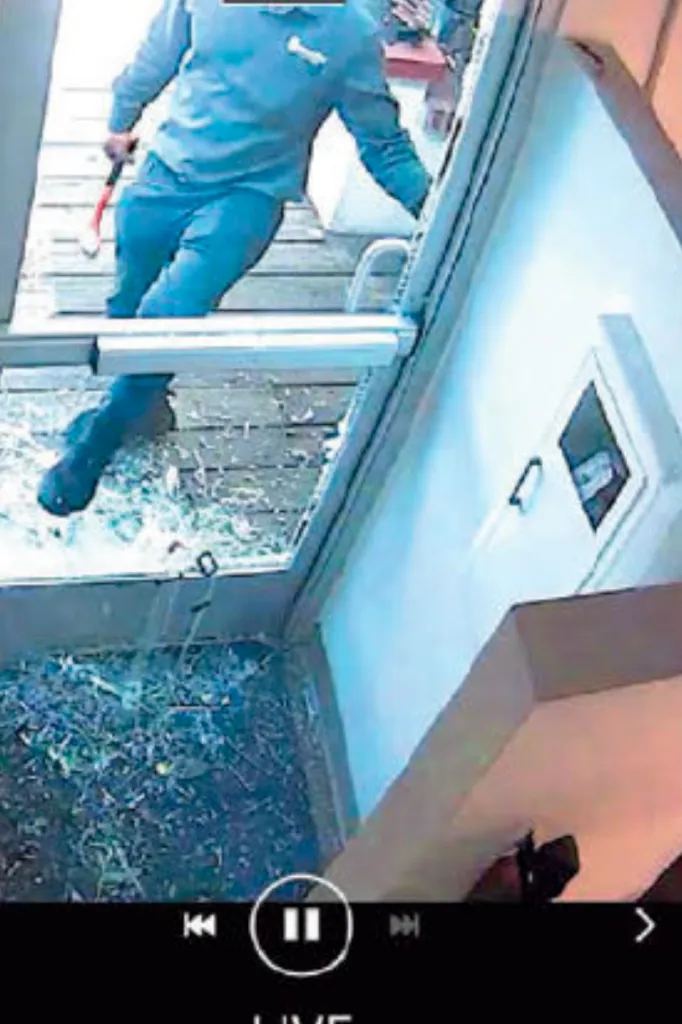 Surveillance footage showing a person holding a crowbar stepping over broken glass.
