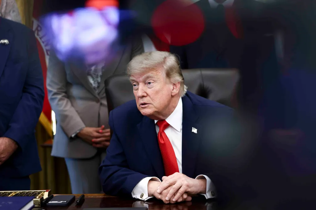 Donald Trump sits at a desk in the Oval Office.