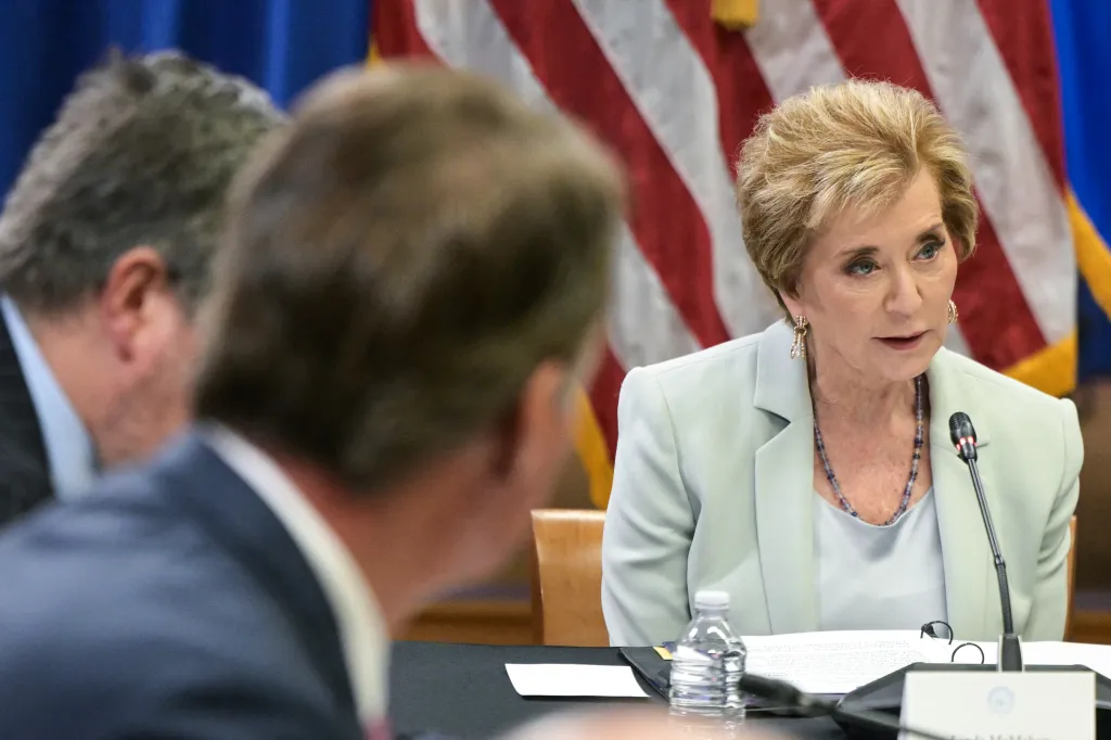 US Secretary of Education Linda McMahon speaking at a round table discussion with an American flag in the background.