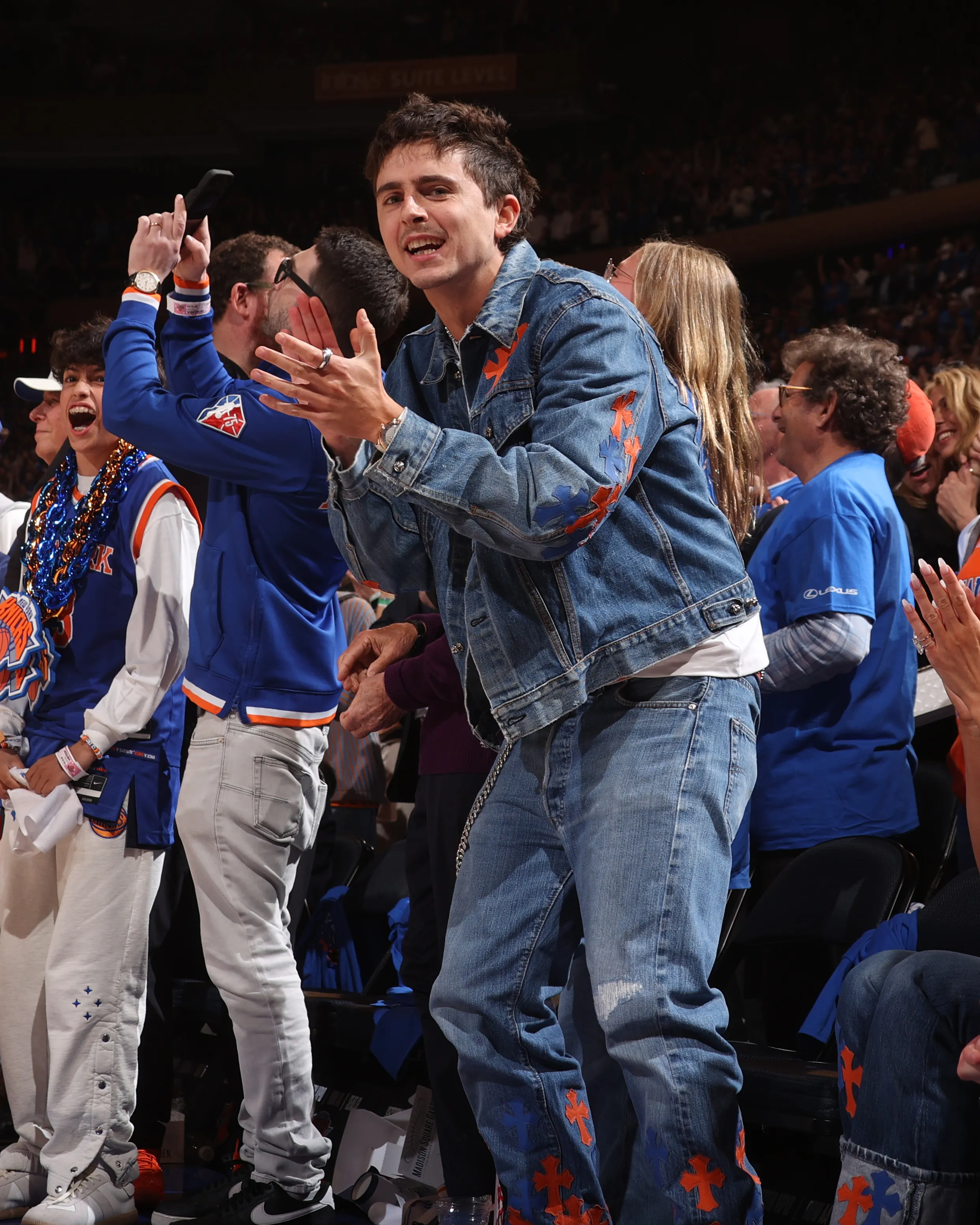 Timothee Chalamet applauding in the stands at Madison Square Garden during an NBA game.
