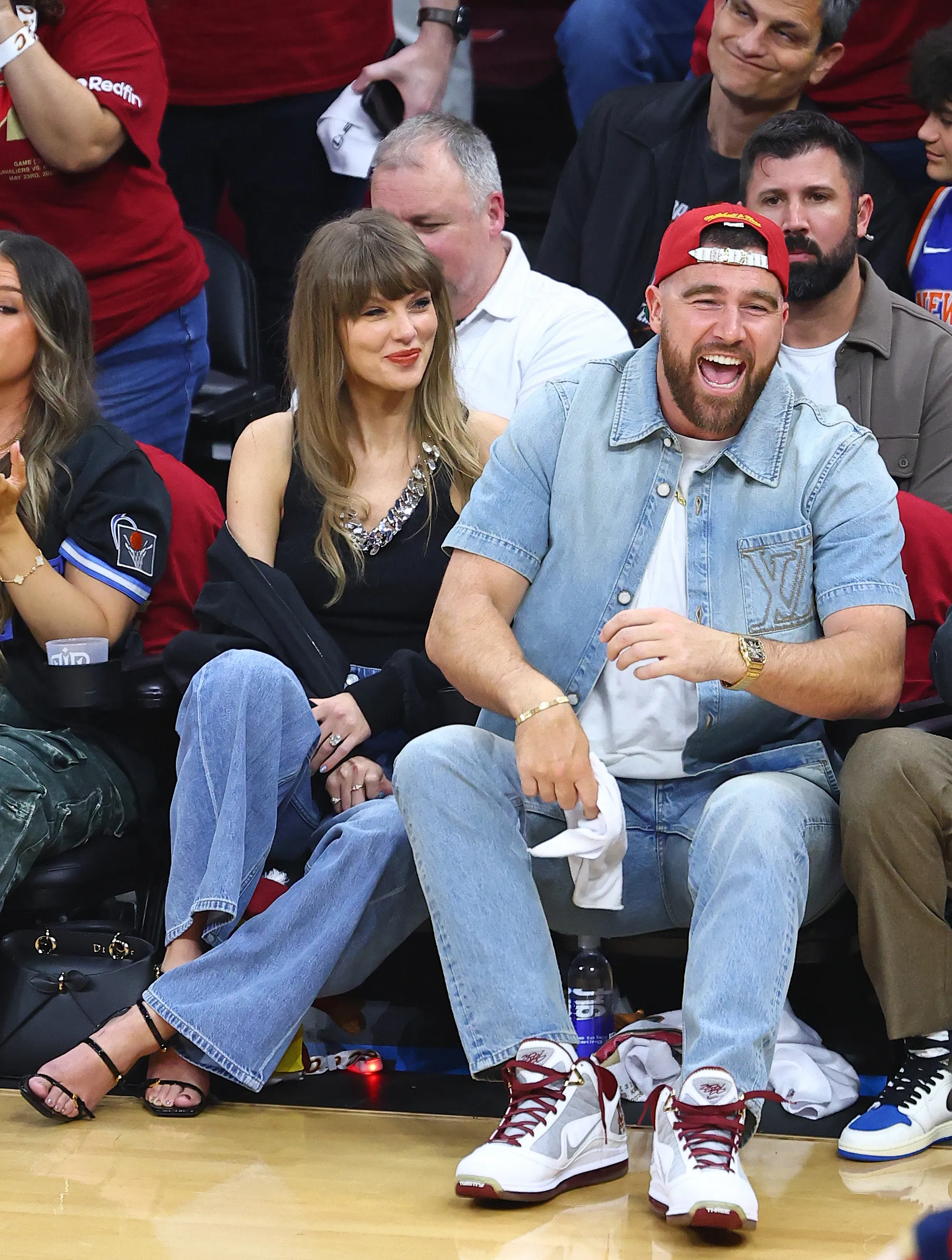 Taylor Swift and Travis Kelce sitting courtside at a basketball game.