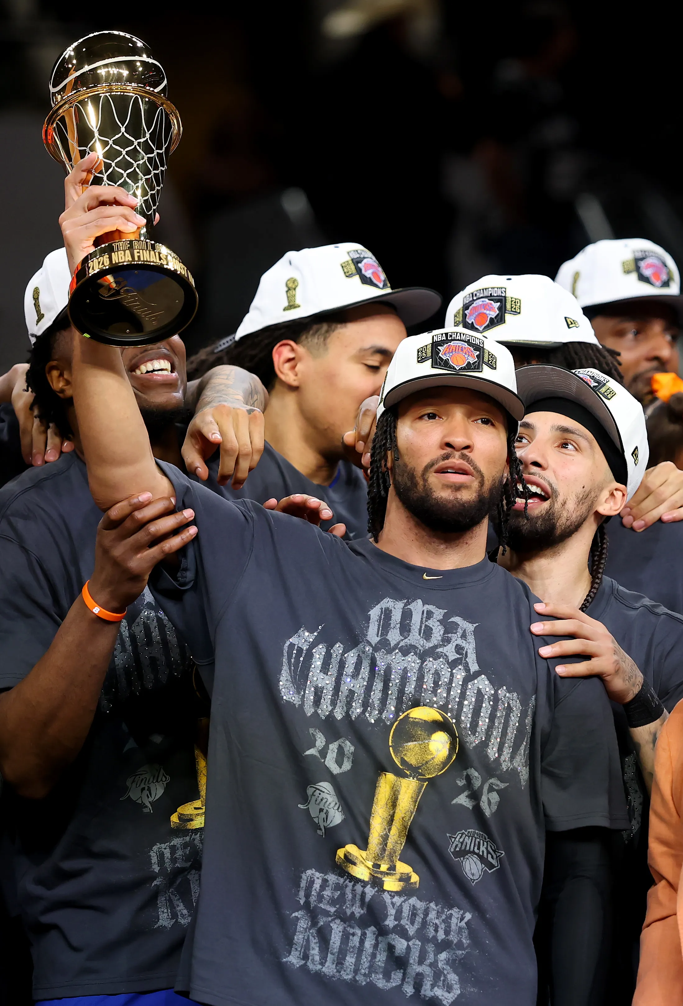 Jalen Brunson holding the Bill Russell NBA Finals Most Valuable Player Award trophy, surrounded by other New York Knicks players.