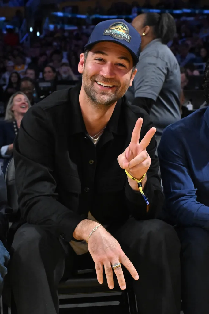 Manuel Garcia-Rulfo smiling and holding up a peace sign at a basketball game.