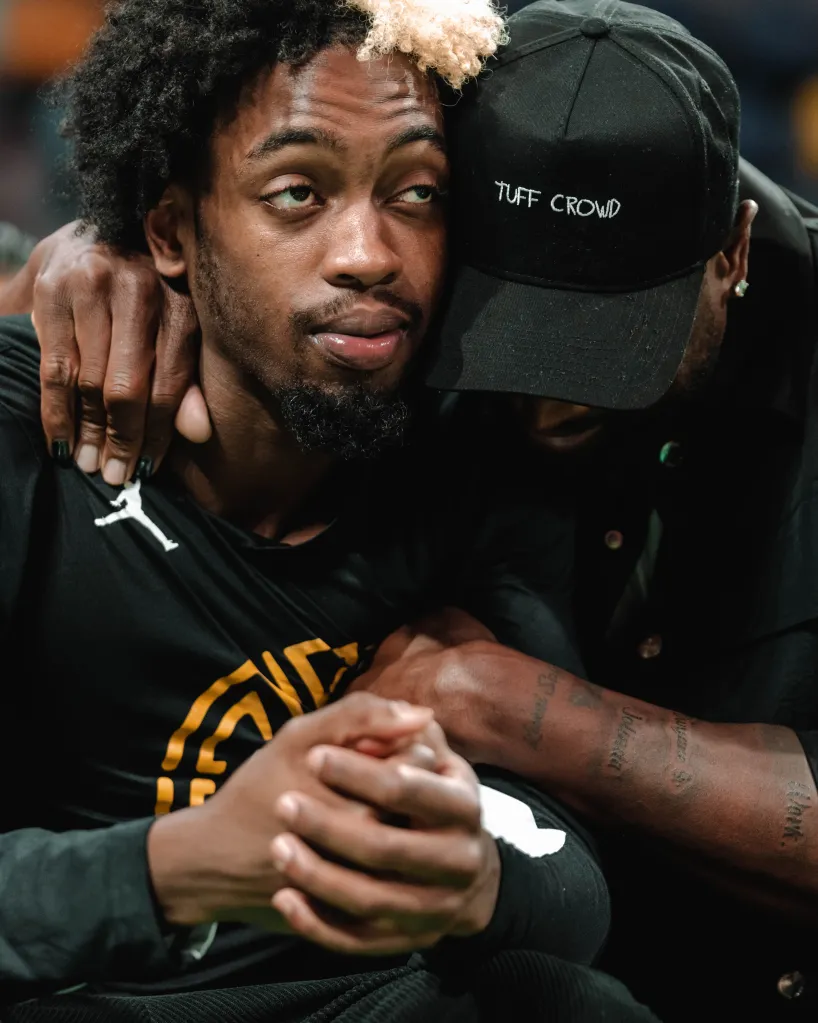 Dwyane Wade hugs Zaire Wade from behind at a basketball game.