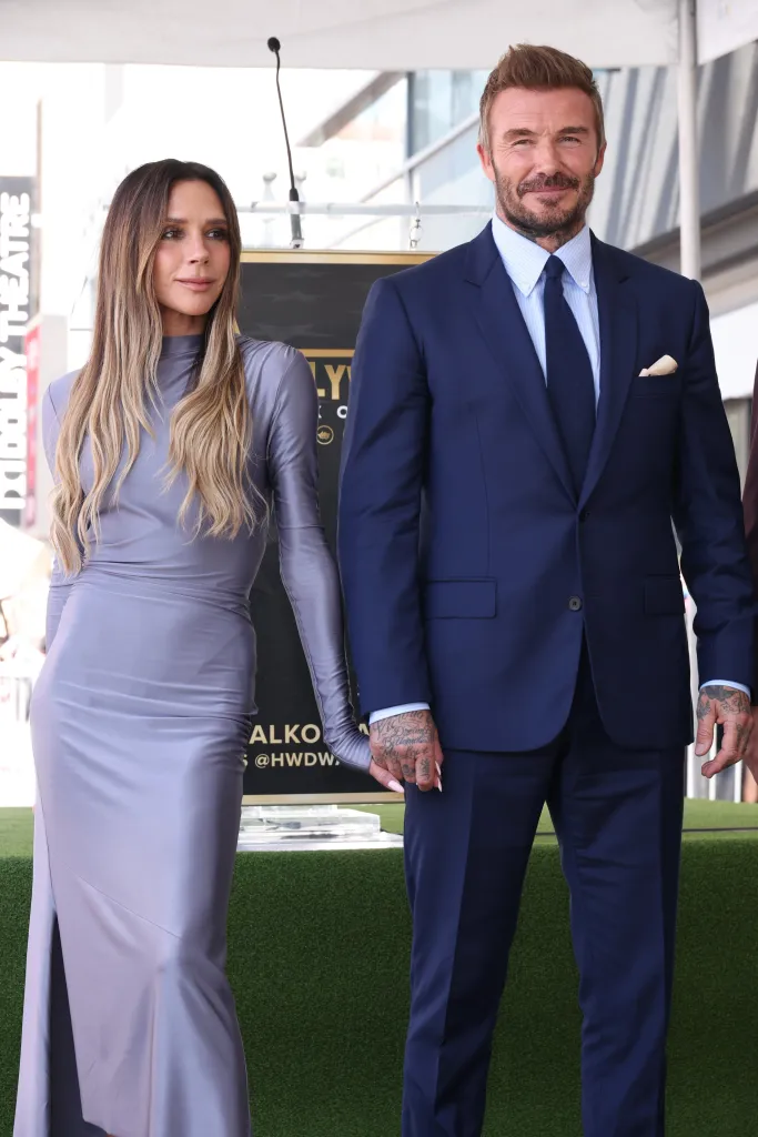 Victoria and David Beckham posing on a green stage.
