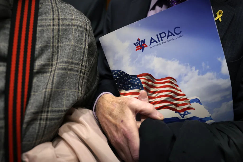 A person's hands holding an AIPAC folder in an elevator.