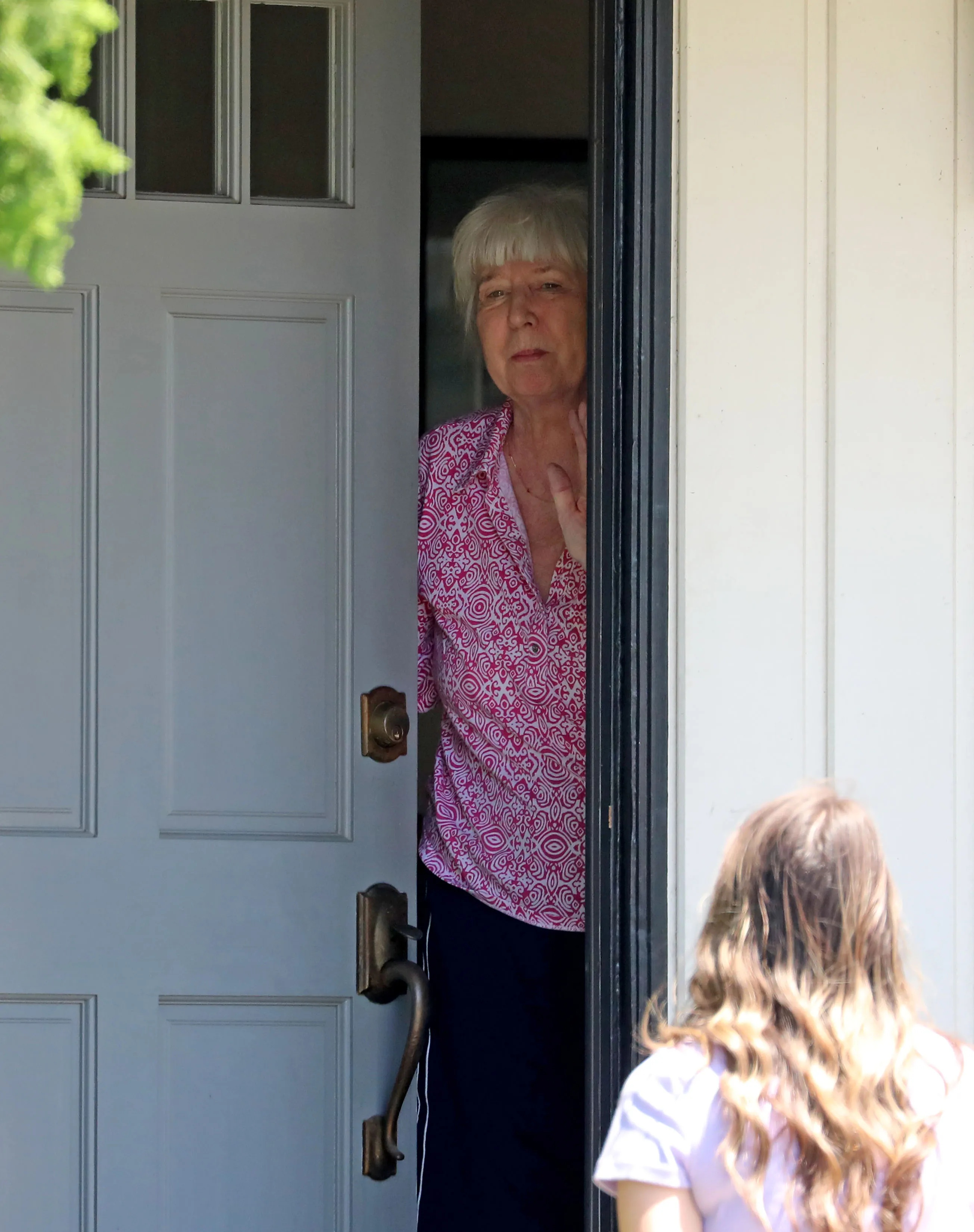 Wendy Gledhill stands in a doorway, talking to someone whose back is to the camera.