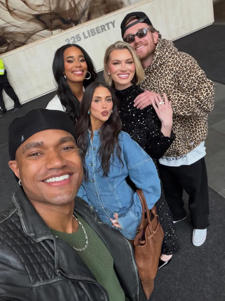 Five people posing for a selfie in front of a building labeled 