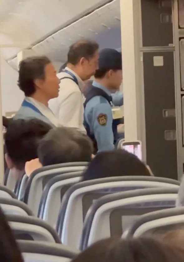 Police officers speaking with a passenger on a diverted flight.