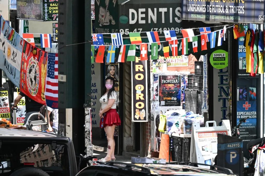 A woman stands outside a suspected sex shop with many flags hanging above.