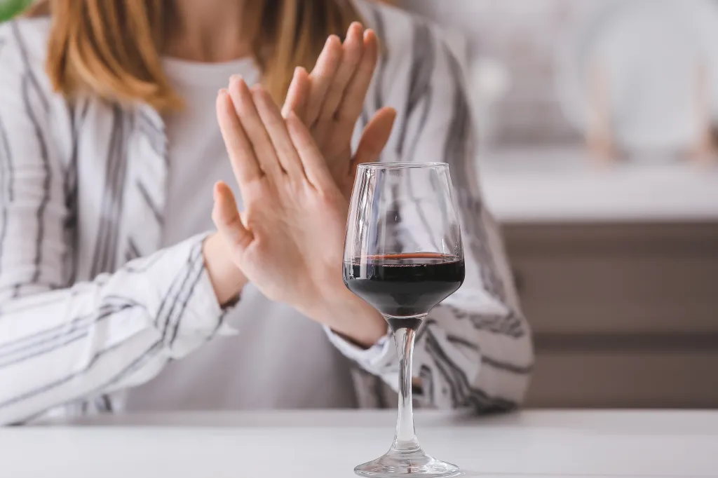 A woman in a white and black striped shirt holds her hands up in a