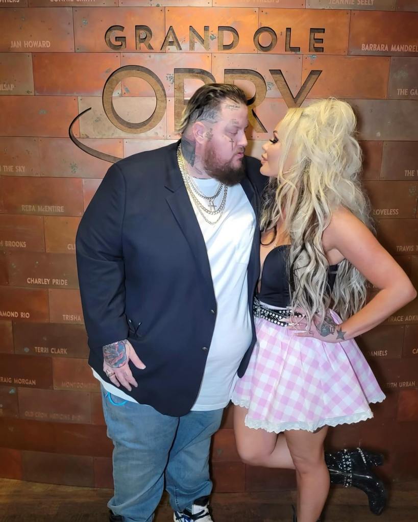 Bunnie XO and Jelly Roll looking at each other in front of a Grand Ole Opry sign.