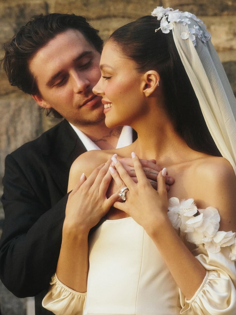 Brooklyn Beckham, in a black suit and white shirt, embraces Nicola Peltz, in a white gown and white veil, during their vow renewal ceremony.