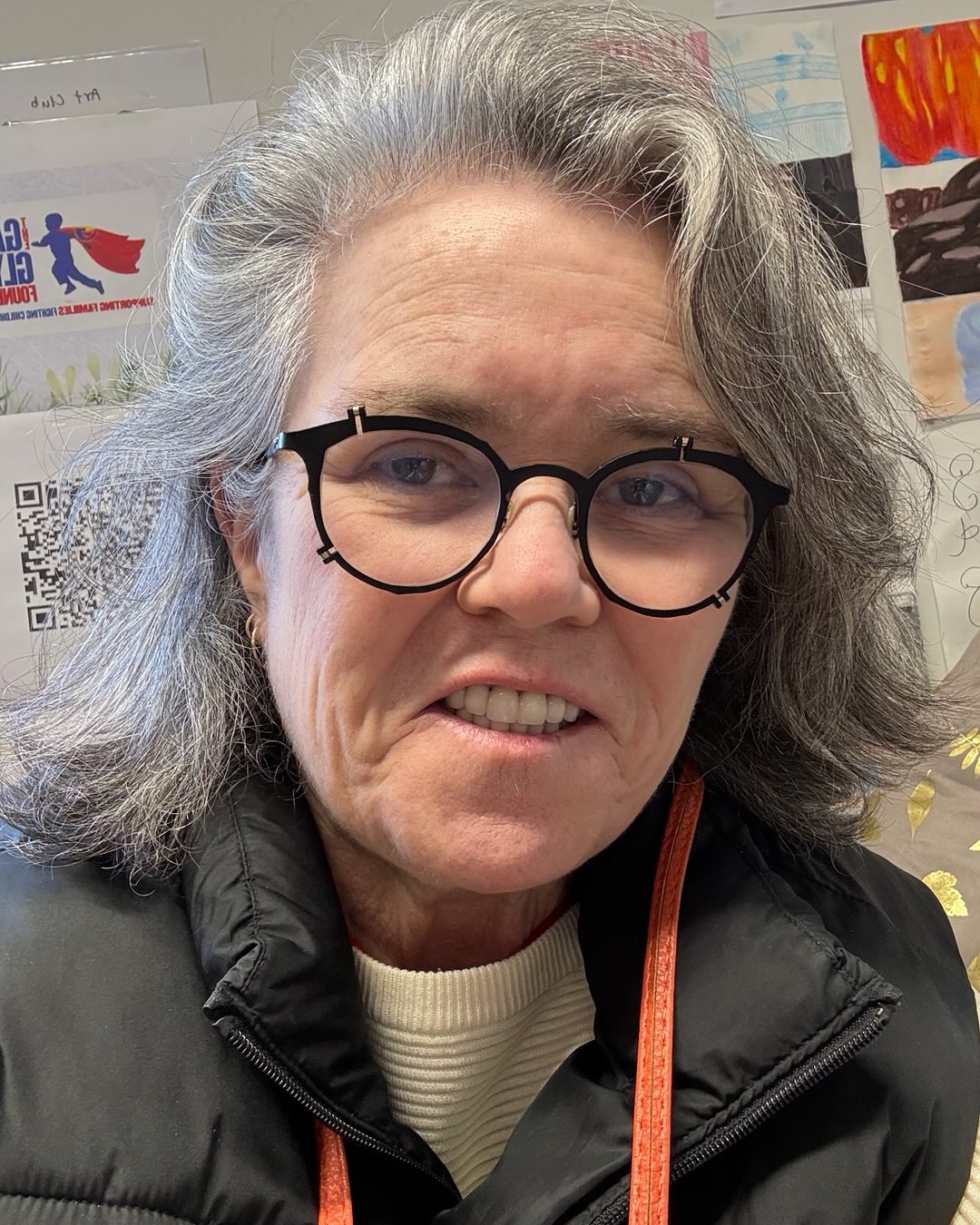 Rosie O'Donnell in a black vest and glasses, making a face.