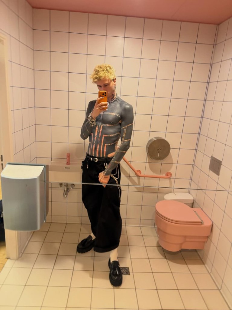 Machine Gun Kelly takes a mirror selfie showing his blacked-out torso and arm tattoos.