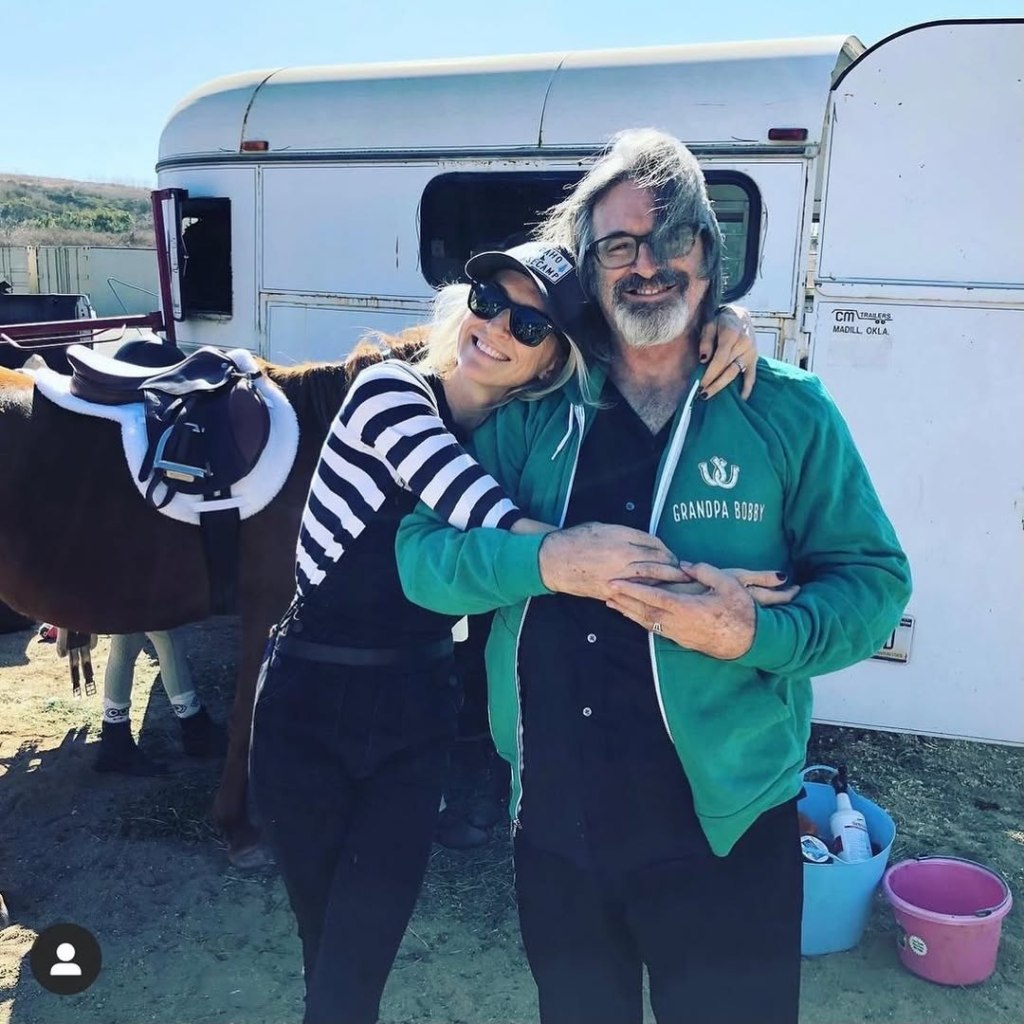 Ever Carradine embracing her father, Robert Carradine, with a horse and trailer in the background.