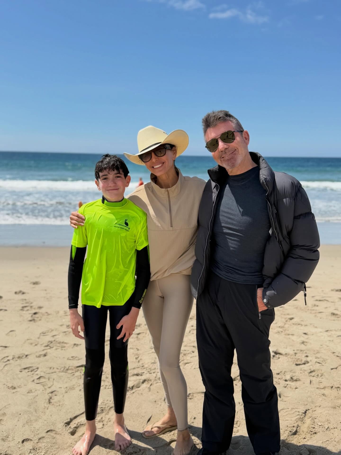 Simon Cowell, Lauren Silverman, and their son Eric on a beach.