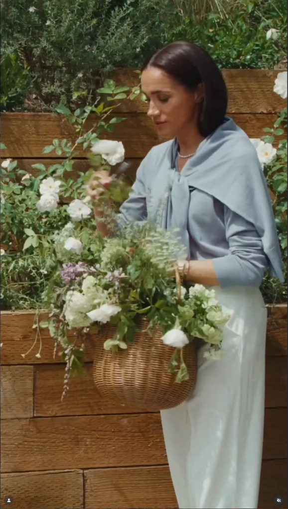 Meghan Markle arranging flowers and herbs in a woven basket.