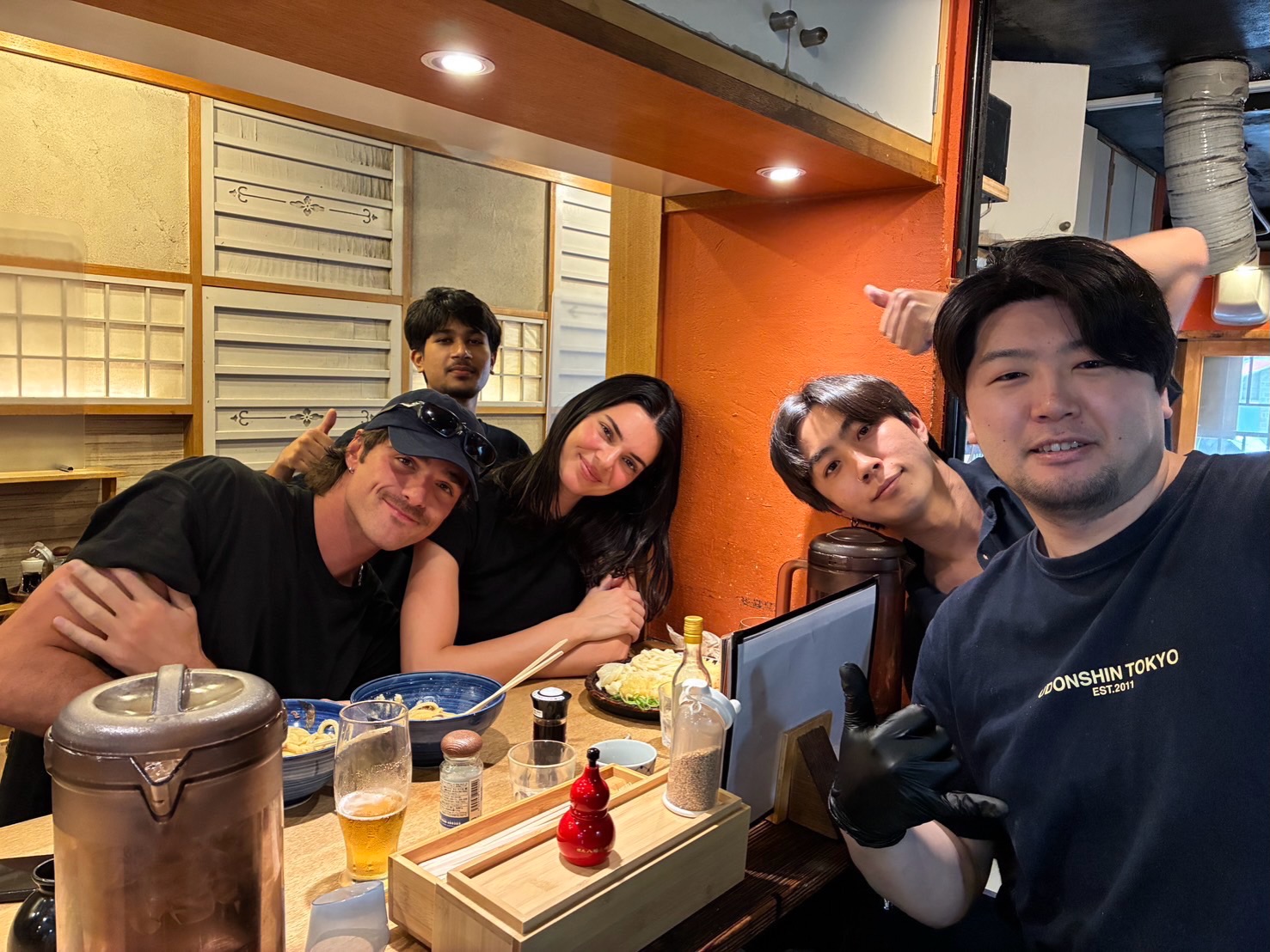 A group of friends, including Kendall Jenner and Jacob Elordi, posing for a photo in a restaurant.