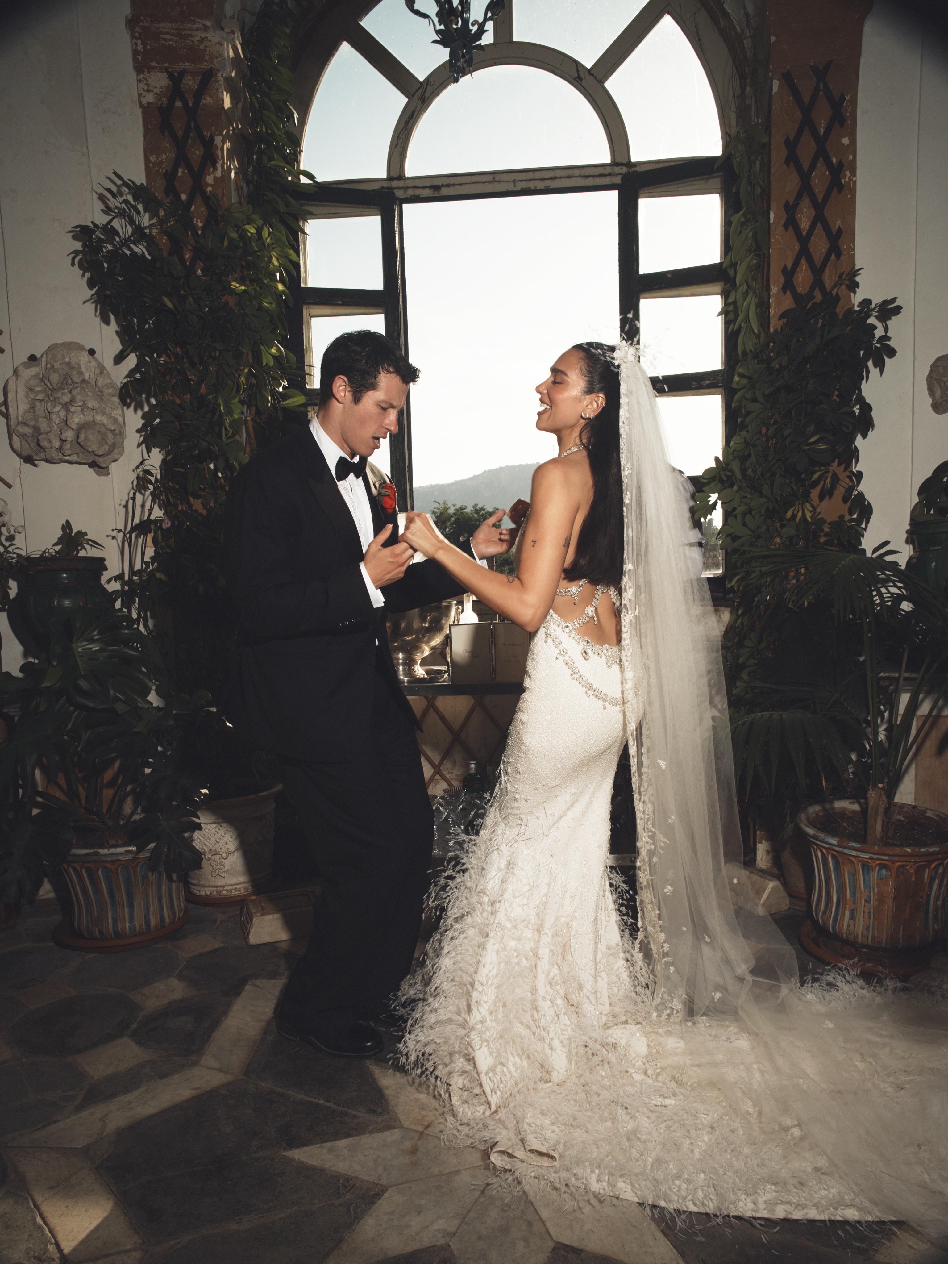 Dua Lipa dancing at her wedding with her husband, both dressed in formal attire.