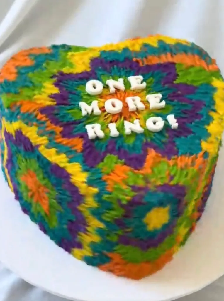A heart-shaped cake with tie-dye frosting that says 