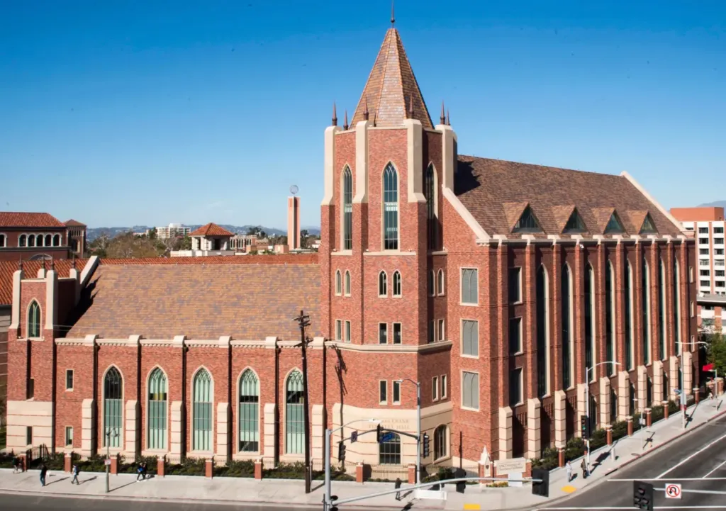 USC Marshall School of Business building under a clear blue sky.