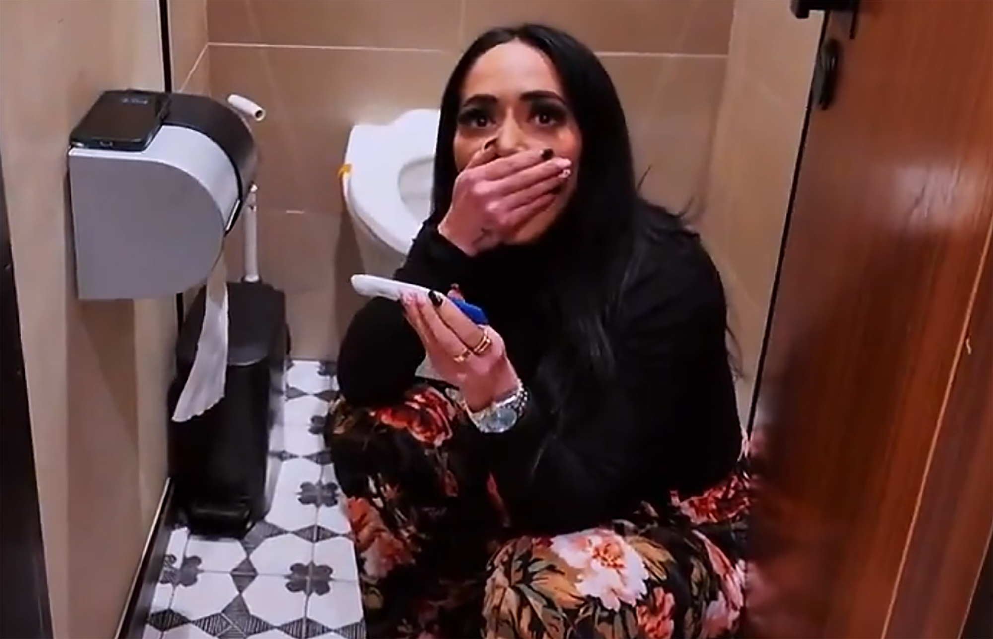 Angelina Pivarnick holds a pregnancy test, covering her mouth in shock.