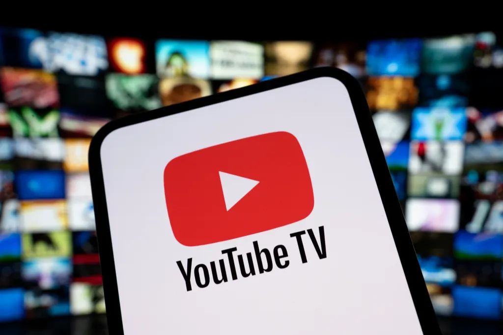 Illustration of the YouTube TV logo on a smartphone screen with a blurred background of a streaming site catalog.