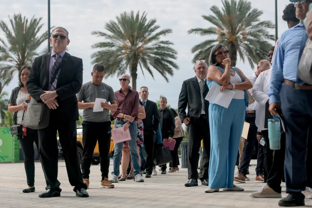 Job seekers line up outdoors for a job fair.