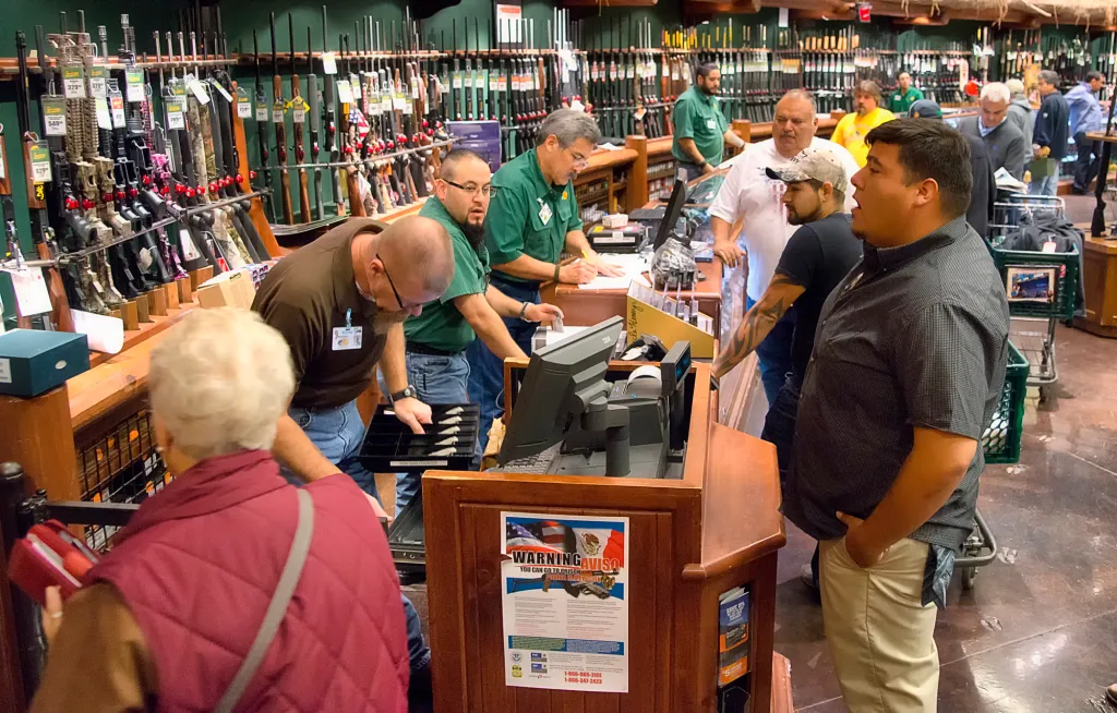 Customers and staff at a gun counter.