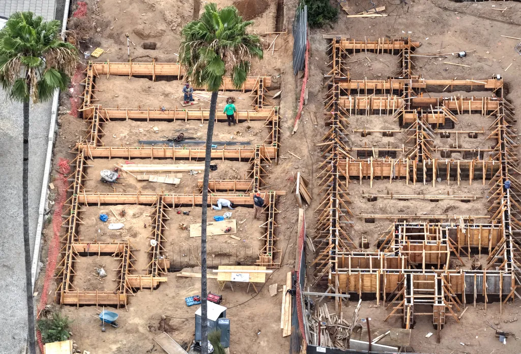 Aerial view of construction workers rebuilding two homes in Altadena, California.